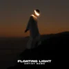 A surreal music album cover featuring a figure in a white robe with a glowing halo around their head, standing on a cliff at sunset with a warm orange sky.